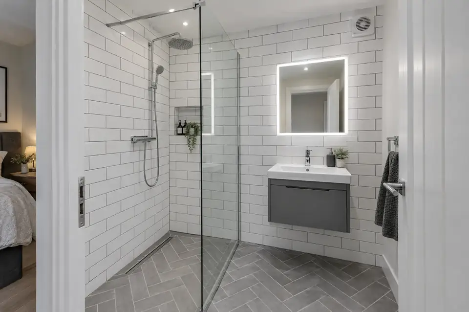 Compact en-suite shower room with white metro tiles, herringbone floor and illuminated mirror