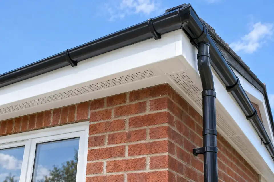 New white uPVC fascias and soffits with black half-round guttering on a brick house