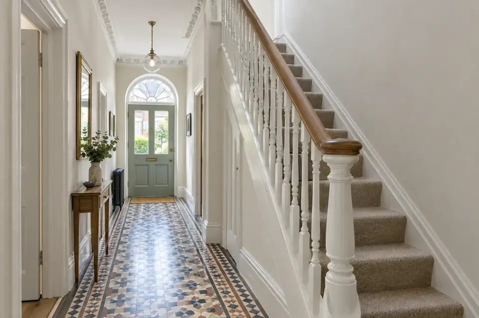 Renovated Victorian hallway with restored tiled floor, new handrail and freshly plastered walls
