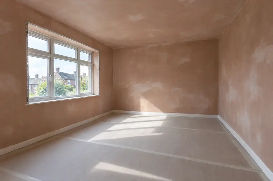Freshly skimmed walls and ceiling drying in an empty room with straight angle beads