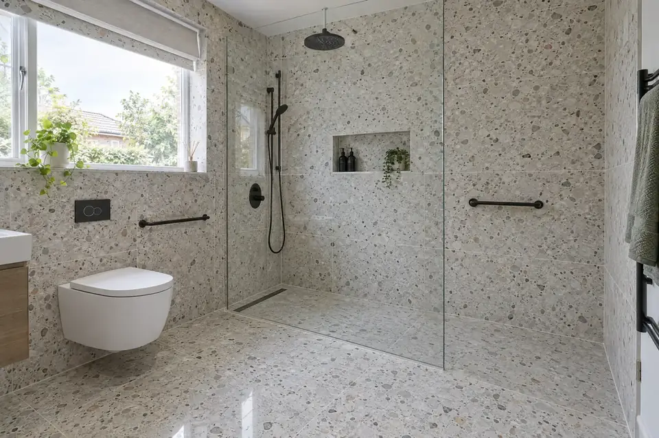 Level-access wet room with terrazzo-effect tiles, linear drain, glass screen and black rainfall shower